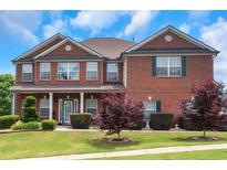 Beautiful two-story brick home featuring a covered front porch and manicured landscaping at 1104 Stepping Stone Ln, Conyers, GA 30012