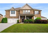 Inviting two-story brick home featuring a manicured lawn, two-car garage, and charming covered front porch at 1520 Gallant Fox Ln, Suwanee, GA 30024
