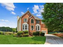 Beautiful two-story brick home boasts a manicured lawn, lush landscaping, and an inviting facade at 2045 Calmwater Ct, Suwanee, GA 30024
