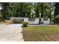 Charming single-story home with white brick, dark trim, front yard, and open carport at 4720 Shoshonee Trl, College Park, GA 30349