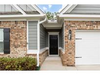 Charming brick home with a black front door, gray siding, and a well-maintained yard and white garage door at 131 Prominence Ct, Canton, GA 30114