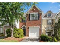 Charming two-story brick townhome with attached garage and manicured landscaping at 208 Magnolia Leaf Dr, Woodstock, GA 30188