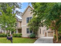 Charming tan two-story home with a detached garage and a well-manicured lawn surrounded by mature trees at 2217 Virginia Ne Pl, Atlanta, GA 30305