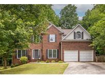 Charming two-story brick home with a two-car garage, manicured lawn, and traditional architectural details at 1130 Timbercreek Ct, Alpharetta, GA 30005
