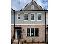 Charming two-story townhome featuring a brick facade, gray siding and a welcoming front door at 1240 Ainsworth Aly # 39, Sugar Hill, GA 30518