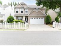 Charming two-story home features a well-manicured lawn, white picket fence, and attached two-car garage at 3442 Old Towne Ln, Cumming, GA 30040