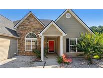 Charming home featuring stone accents, a cozy porch, and a vibrant red front door at 1625 Alcovy River Dr, Dacula, GA 30019