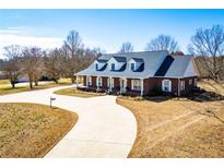 Inviting brick home featuring a long drive, well-manicured lawn and a charming covered front porch at 111 Dixson Rd, Bowdon, GA 30108