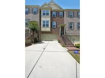 Inviting townhome with brick facade, two-car garage, and landscaped entrance, secured with an ADT security system at 3692 Lambert Ne Ln, Brookhaven, GA 30319