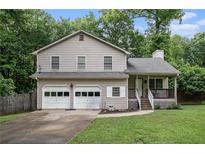 Charming two-story home with a two-car garage and inviting front porch nestled amongst the trees at 1888 Kelvin Dr, Lawrenceville, GA 30043