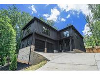 Modern two-story home with dark siding, a two-car garage, and beautiful natural landscaping at 4276 Lindsey Ne Way, Roswell, GA 30075