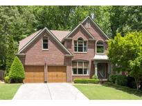 Charming two-story brick home with a well-manicured lawn and a two-car garage nestled among lush trees at 5034 Kingsbridge Pass, Powder Springs, GA 30127