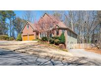 Charming two-story brick home featuring an attached two-car garage and mature landscaping on a sunny day at 5034 Kingsbridge Pass, Powder Springs, GA 30127