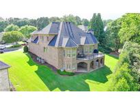 Stunning brick home featuring a large balcony overlooking a lush green lawn and mature trees at 8340 Royal Melbourne Way, Duluth, GA 30097