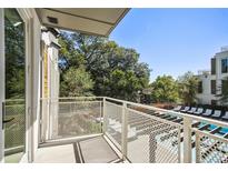 A balcony overlooks a pool and green trees on a sunny day at 775 Juniper Ne St # 334, Atlanta, GA 30308