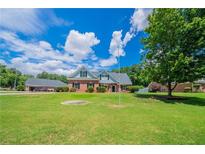 Inviting brick home featuring a beautifully manicured front yard under a partly cloudy sky at 1480 Holly Brook Rd, Snellville, GA 30078