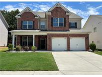 Two-story brick home featuring an attached two-car garage, well-maintained lawn, and an inviting covered front porch at 1777 Weatherbrook Cir, Lawrenceville, GA 30043