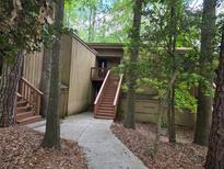 Exterior view of a brown two-story home surrounded by lush greenery and a walkway to the front door at 5818 Par Four Ct, Lithonia, GA 30038