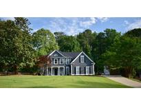 Beautiful two-story home with dark siding, white trim, mature trees and a large manicured front lawn at 219 Maple Creek, Woodstock, GA 30188