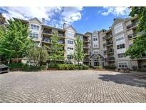 Beautiful condo building exterior with lush landscaping, balconies, and a paved parking area at 2110 River Green Nw Dr # 2110, Atlanta, GA 30327