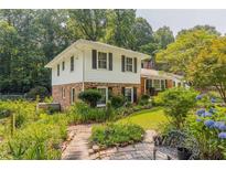 Charming two-story home featuring brick and siding exterior, surrounded by lush landscaping and mature trees at 6825 Castleton Dr, Atlanta, GA 30328