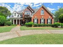 Brick two-story home featuring a meticulously manicured lawn and driveway, and a covered entryway with elegant white columns at 3049 Brightwood Se Ln, Marietta, GA 30067