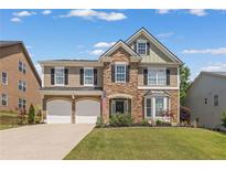 Charming two-story home features a stone and vinyl exterior, two-car garage, manicured lawn, and an inviting front porch at 5415 Fieldfreen Dr, Cumming, GA 30028