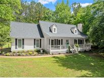 Charming one-story home featuring a welcoming front porch, a well-manicured lawn and beautiful surrounding trees at 5902 Wills Orchard Rd, Cumming, GA 30040