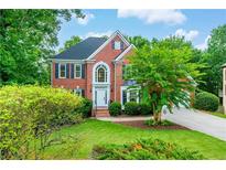 Beautiful two-story brick home with manicured lawn, lush trees, and charming curb appeal at 4910 Aldbury Ln, Suwanee, GA 30024