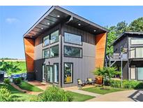 Modern two-story home with a gray exterior, wood accents, large windows, and well-manicured landscaping at 3120 Godby Rd, Atlanta, GA 30349