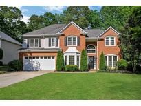 Two-story brick home with a manicured lawn and a two car garage and beautiful, mature trees at 1411 Blackland Trl, Lawrenceville, GA 30043