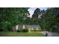 Brick single-story home with manicured lawn, bushes, and a private driveway surrounded by mature trees at 3250 Valley Bend Rd, South Fulton, GA 30349