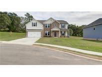 Inviting two-story home showcasing a manicured lawn, brick accents, and a convenient two-car garage at 238 Linford Dr, Locust Grove, GA 30248