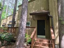 Charming home featuring a covered front entrance and wooden deck, surrounded by lush greenery and mature trees at 5826 Par Four Ct, Lithonia, GA 30038