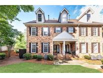 Charming brick townhouse featuring dormer windows, a covered front porch, and professionally landscaped yard at 2610 Oglethorpe Ne Cir, Brookhaven, GA 30319