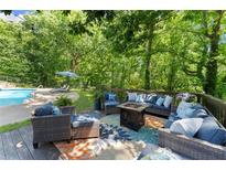 Inviting outdoor deck with stylish seating, fire pit, and colorful rug overlooking the pool and lush backyard at 2936 Summitop Ne Rd, Marietta, GA 30066