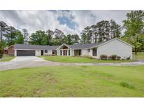 Stunning white brick home featuring a modern design, lush lawn, and a spacious driveway leading to an attached garage at 4700 Cascade Sw Rd, Atlanta, GA 30331