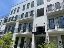 Modern townhouse with white brick facade, dark trim, multiple balconies, and professional landscaping at 1276 Longreen Terrace Nw # 115, Atlanta, GA 30318