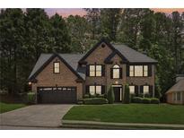 Charming two-story brick home featuring a well-manicured lawn and attached two-car garage at 1045 River Valley Dr, Dacula, GA 30019