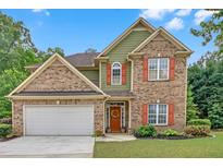 Charming two-story brick home with an attached garage and colorful, welcoming curb appeal at 1990 Cooper Lakes Dr, Grayson, GA 30017
