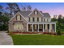 Charming two-story brick home with a welcoming front porch and meticulously manicured lawn at 1073 Sweet Mia Ln, Powder Springs, GA 30127