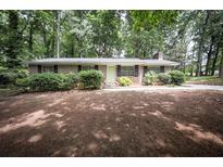 Ranch style home with brick exterior, green door, manicured front yard with mature trees and shrubs at 5666 Goldfield Dr, Acworth, GA 30102