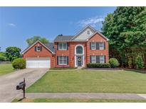 Charming brick home featuring a well-manicured lawn, two-car garage, and beautiful landscaping at 1370 Stoney Field Place, Lawrenceville, GA 30043