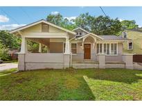 Charming home featuring a covered porch, brick facade, and well-manicured lawn at 1667 Sylvan Sw Rd, Atlanta, GA 30310