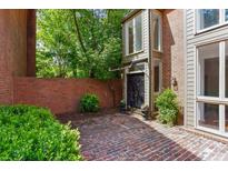 Charming brick home featuring a brick courtyard, black front door and mature landscaping at 49 Willow Gln, Atlanta, GA 30342
