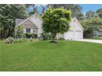 Charming home featuring lush green lawn, two-car garage, beautiful landscaping with a mix of trees and flowering plants at 3001 Garland Sw Dr, Marietta, GA 30008