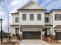 Charming townhouse features a white brick exterior, black windows, and a two-car garage, enhancing curb appeal at 711 Dodd N Ln # 166, Buford, GA 30518