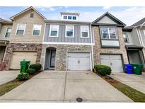 Charming townhome showcasing stone accents, a single-car garage, and well-maintained landscaping at 4922 Longview Walk, Decatur, GA 30035