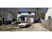 Two-story home featuring a driveway with vintage car and a partially wooded lot at 1679 Emerald Sw Ave, Atlanta, GA 30310