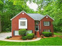 Charming two-story brick home with a well-manicured lawn, lush landscaping, and a welcoming front entrance at 827 Pinehurst Dr, Woodstock, GA 30188
